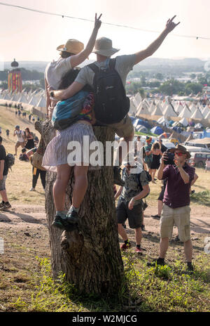 Festivalbesucher posieren für ein Foto über dem Tipidorf an Glastonbury 2019 Stockfoto