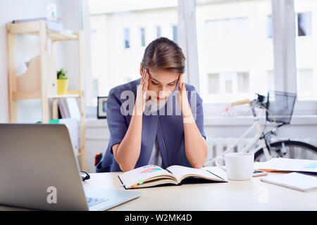 Betont, Geschäftsfrau, Sitzen, die von Ihrem Schreibtisch im Büro Stockfoto