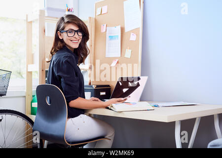 Gerne Frau sitzt "vom Schreibtisch zu Hause Büro Stockfoto