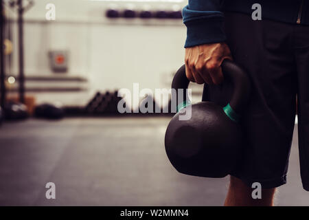 Nahaufnahme von Mann mit kettlebell im modernen Fitnessraum Stockfoto