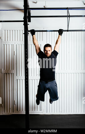 Muskulöse Mann ein Training im Fitnessstudio tun kipping Übungen Stockfoto
