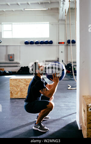 Junger Mann performing slam Ball Übungen in der Turnhalle Stockfoto