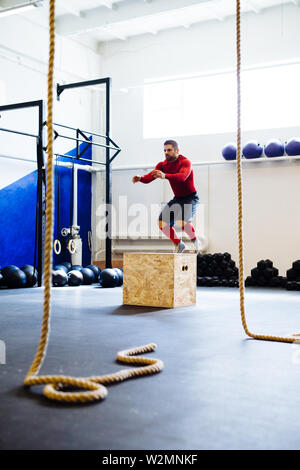 Muskulöse Mann tun Jumping Box Übungen in der Turnhalle Stockfoto
