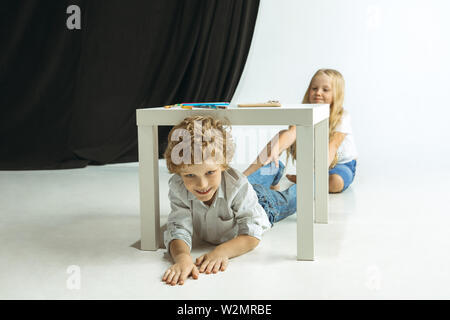 Junge und Mädchen Vorbereitung auf die Schule nach einer langen Sommerpause. Zurück zu Schule. Wenig kaukasischen Modelle zusammen spielen auf Studio Hintergrund. Kindheit, Bildung, Urlaub oder Hausaufgaben Konzept. Stockfoto