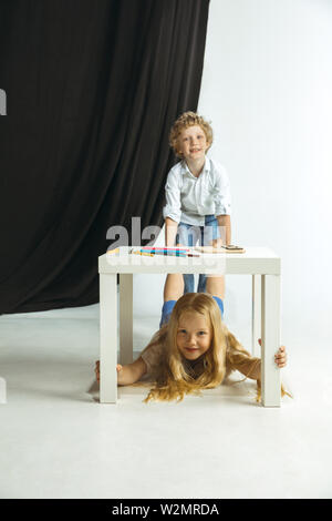 Junge und Mädchen Vorbereitung auf die Schule nach einer langen Sommerpause. Zurück zu Schule. Wenig kaukasischen Modelle zusammen spielen auf Studio Hintergrund. Kindheit, Bildung, Urlaub oder Hausaufgaben Konzept. Stockfoto