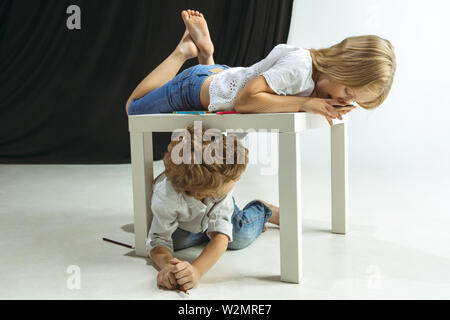 Junge und Mädchen Vorbereitung auf die Schule nach einer langen Sommerpause. Zurück zu Schule. Wenig kaukasischen Modelle zusammen spielen auf Studio Hintergrund. Kindheit, Bildung, Urlaub oder Hausaufgaben Konzept. Stockfoto