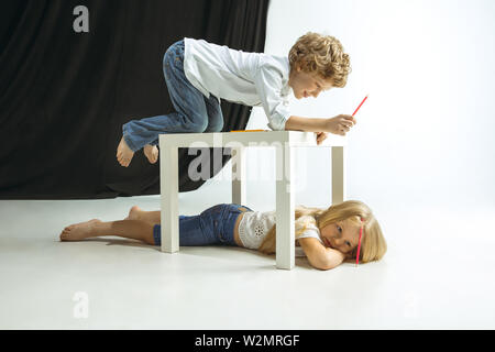 Junge und Mädchen Vorbereitung auf die Schule nach einer langen Sommerpause. Zurück zu Schule. Wenig kaukasischen Modelle zusammen spielen auf Studio Hintergrund. Kindheit, Bildung, Urlaub oder Hausaufgaben Konzept. Stockfoto