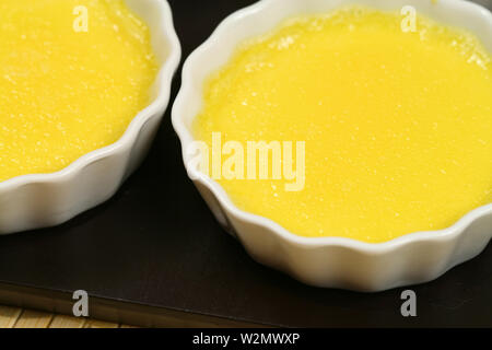 Crème brûlée vor karamelisierung - Nahaufnahme von custard gelb Creme in Porzellan Förmchen Stockfoto