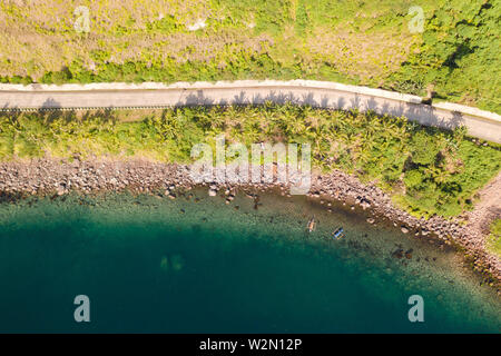Konkrete Straße entlang der Küste, Blick von oben. Steinige Küste mit einem Blue Bay, Philippinen. Stockfoto