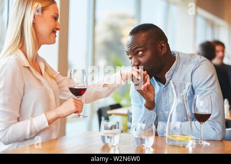 Junge afrikanische Mann gibt seiner Freundin die Hand küssen im Restaurant Stockfoto