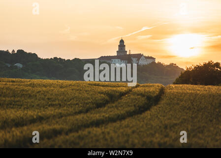 Erzabtei Pannonhalma mit Weizenfeld und Pfad auf Sonnenuntergang im Sommer Stockfoto