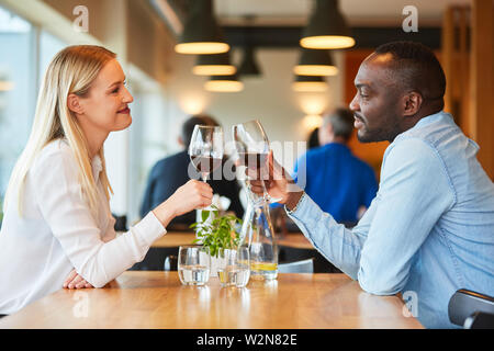 Multikulturelle junges Paar mit einem Drink, während Sie ein Rendezvous im Restaurant Stockfoto