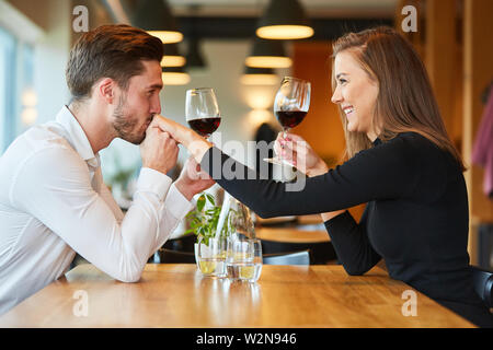Verliebter Mann gibt seiner Freundin einen Kuss beim Trinken von Rotwein im Restaurant Stockfoto