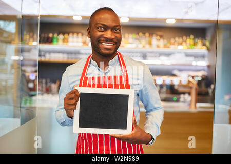 Afrikanische Kellner hält leer Schild vor der Bar oder im Restaurant Stockfoto