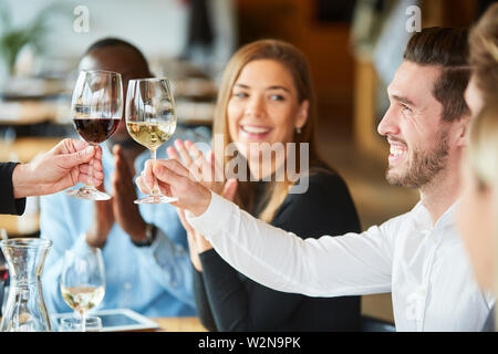 Junger Mann feiert mit Freunden im Restaurant und Toasten mit einem Glas Wein Stockfoto