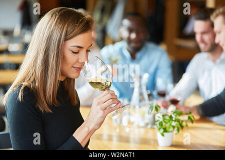 Junge Frau riecht ein Glas Weißwein während einer Weinprobe oder Verkostung Stockfoto