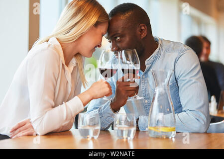 Multikulturelle junge Paar verliebt in Wein im Restaurant Stockfoto