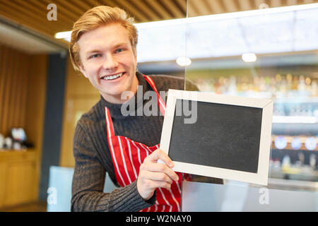 Lächelnd Kellner hält ein leeres Namensschild an der Tür des Restaurants Stockfoto
