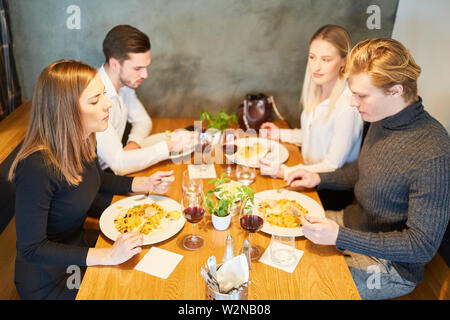 Junge Menschen, die gemeinsam Mittag- oder Abendessen im Restaurant Stockfoto
