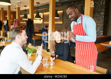 Afrikanische Kellner bestellen der Gäste Paar auf einem Notizblock Stockfoto