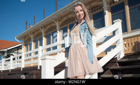 Junge fröhliches Mädchen, der am Ufer des Meeres. Junge blonde Frau lächelnd. Junge trendige Frau auf einem Spaziergang, Lifestyle. Stockfoto