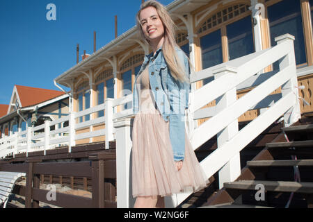 Junge fröhliches Mädchen, der am Ufer des Meeres. Junge blonde Frau lächelnd. Junge trendige Frau auf einem Spaziergang, Lifestyle. Stockfoto