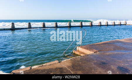 Strand Gezeiten Swimmingpool mit Surfer Surfen Ozean Wellen brechen Absturz auf flache Riffe Stockfoto