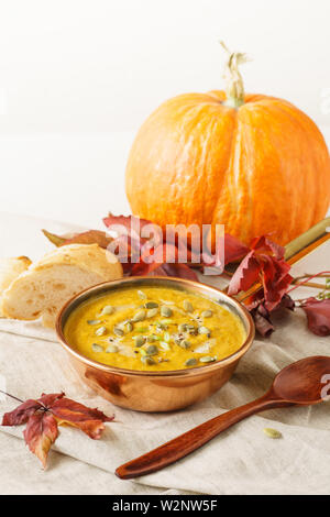 Kürbis Suppe in einer Kupfer Topf mit Samen serviert. Herbst Mittagessen Konzept mit kopieren. Stockfoto