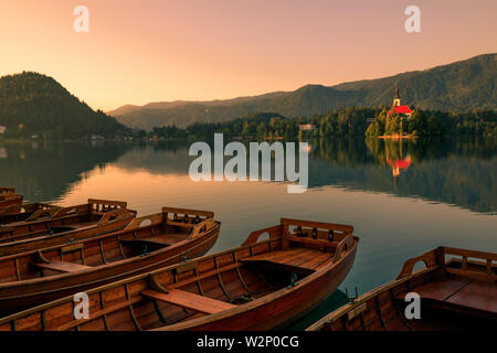 Hölzerne Boote am See Bled auf einem Pier im Sommer während Sonnenaufgang Sonnenuntergang Stockfoto