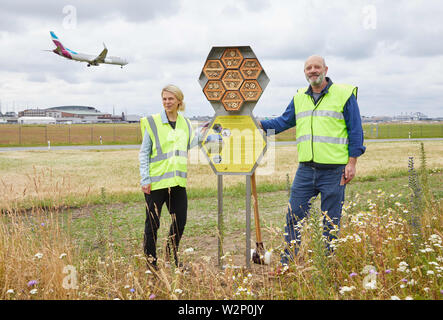 Hamburg, Deutschland. 10. Juli 2019. Anna Binczik, Biologe der Deutschen Wildlife Foundation, und Ingo Fehr, Flughafen Imker, stehen bei einem Insekt Haus für Wilde Bienen in der Nähe der Start- und Landebahn während einer Pressekonferenz anlässlich der Eröffnung der neuen Insekt Hotel. Eine Eurowings Flugzeug im Hintergrund. Quelle: Georg Wendt/dpa/Alamy leben Nachrichten Stockfoto