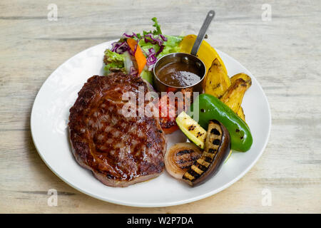 Bis Gegrilltes Rib Eye Steak mit Gemüse, Bratkartoffeln, Grill hausgemachte Soße in eine weiße Platte isoliert, professionellen italienischen Koch bi Stockfoto