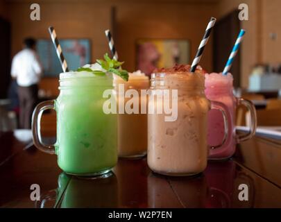 Nahaufnahme von drei verschiedenen aromatisierten leckeren Thai Milch Tee auf Ein Holztisch in einem Café Stockfoto