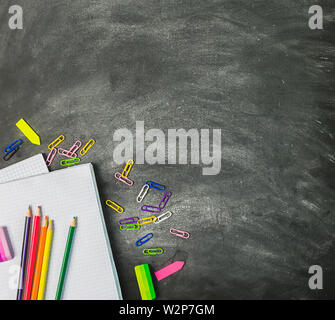Pädagogische liefert Notebooks Kugelschreiber Bleistifte vor dem Hintergrund einer Kreidetafel. Das Konzept der Schule. Flache Layout Stockfoto