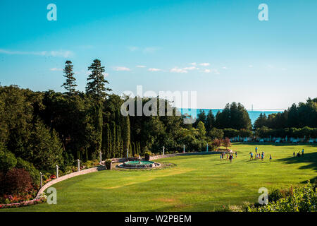 Schuss in den Gärten des Grand Hotel an einem sonnigen Tag mit der Mackinac Bridge im Hintergrund Stockfoto