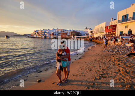 Mykonos, griechische Insel Mikonos, Teil der Kykladen, Griechenland. touristischen Hafen Wahrzeichen Little Venice Beach mit Touristen genießen den Sonnenuntergang Stockfoto