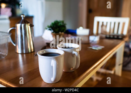 Nahaufnahme von zwei Tassen Kaffee oder schwarzen Tee puerh mit Edelstahl Französisch drücken Sie auf Holz rustikale Tabelle im Land home Stockfoto