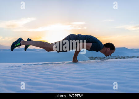 Man Trainieren tun Regal übung Balancieren auf Fäuste in White Sands Dunes National Monument in New Mexico Sonnenuntergang Stockfoto