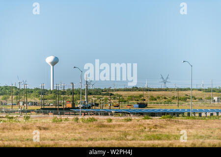 Snyder, USA - Juni 7, 2019: Blick auf Wasserturm solar panel Farm und Stromleitungen in Texas Landschaft Industriestadt und Horizon Stockfoto