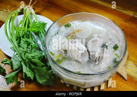 Reisbrei mit Schweinefleisch Knochen heiße Suppe und frisches Gemüse Stockfoto