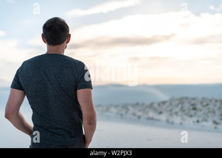 Mann zurück ständigen Closeup auf Sand in White Sands Dunes National Monument in New Mexico bei Sonnenuntergang über Horizont und Orgel Bergen Stockfoto