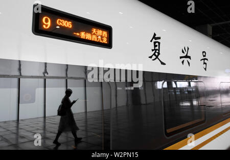 (190710) - Tianjin, Juli 10, 2019 (Xinhua) - ein Fahrgast Spaziergänge Bullet Train G305 bei Tianjin West Railway Station in North China Tianjin, 10. Juli 2019. Die mehr als 1.100 Passagiere, Bullet Train G305 Tianjin bei 10: 58 Uhr und wird in Hong Kong West Kowloon Station rund 10 Stunden später ankommen, nach Tianjin der Eisenbahnverwaltungen. Die 2.450 km lange Strecke wird durch mehrere Stationen einschließlich Xiongan Baiyangdian Station im neuen Bereich laufen. Ein zweiter Sitz für die 10-stündige Fahrt kostet 1,092.5 Yuan (etwa 159 US-Dollar). (Xinhua / Xing Guangli) Stockfoto