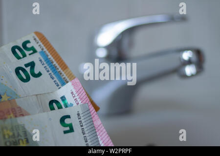 Close up Chrom Waschbecken mit Euro-Banknoten. Konzept für die Erhöhung der Wasserpreise und Haushalt Budgetplanung. Steigender Verbrauch Stockfoto