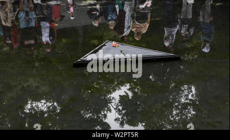 Berlin, Deutschland. 10. Juli 2019. Besucher stand auf dem Teich auf dem Gelände der Gedenkstätte für die Sinti und Roma in der Zeit des Nationalsozialismus im Tiergarten ermordet. Bisher unbekannte Täter beschädigten eine Glasscheibe auf das Denkmal am Abend. Die Sicherheit des Staates die Polizei ermittelt. Credit: Paul Zinken/dpa/Alamy leben Nachrichten Stockfoto