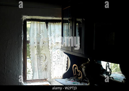 Ein Fenster in einem weiß getünchten Hütte mit einem Holzrahmen, Lacy Bettwäsche gestärkte Vorhang. Das Innere des Hauses. Die Ukraine, die Kosaken Stockfoto