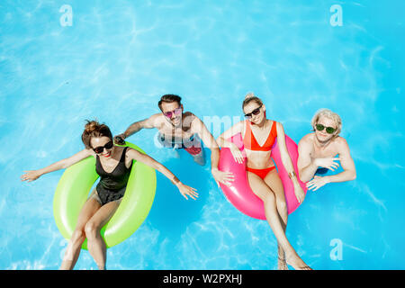 Gruppe von einer glücklichen Freunde, Spaß haben, Schwimmen mit aufblasbaren Spielzeug in den Swimmingpool im Freien, Ansicht von oben Stockfoto