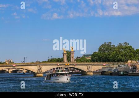 Schöne Panoramasicht auf ein Boot mit Menschen auf der Seine in Paris. Im Hintergrund steht die Brücke Pont des Invalides. Stockfoto