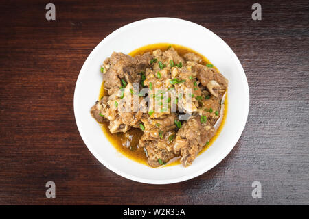 Chinesische geschmorte Schweinerippchen mit Pfeffer und Knoblauch Sauce in weißer Teller auf dem Tisch Stockfoto