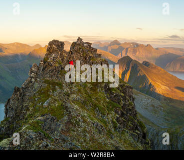 Man Klettern auf einem steilen Berg in der zerklüfteten Landschaft der Insel Senja, Troms Stockfoto