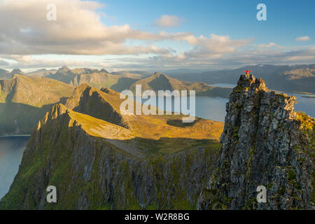 Mann, der an der Spitze einer Pinnacle mit Blick über die Landschaft der Insel Senja, Troms Stockfoto