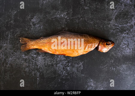 Hohen Winkel in der Nähe von One frisch geräucherte ganze Forelle auf schwarzem Schiefer. Stockfoto